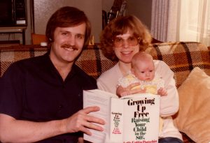 Paul, Sue and baby Annie with the book "Growing Up Free: Raising Your Child in the 80s"